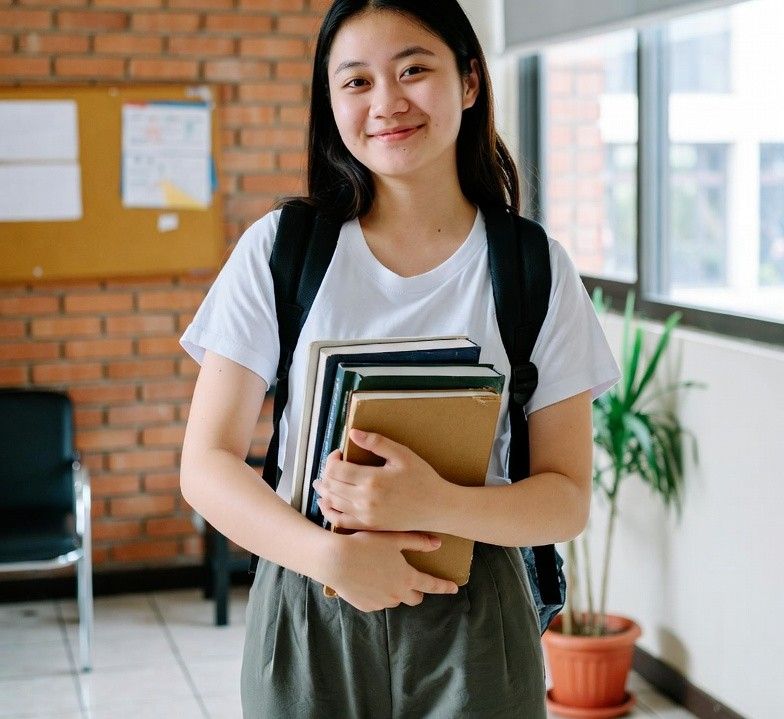 a student happily holding used textbooks in a campus lounge